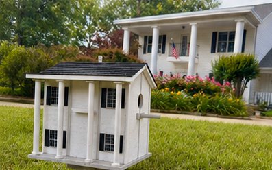 Custom columned birdhouse in front of the home it matches