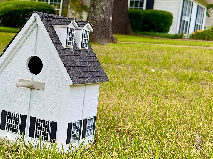 Cottage birdhouse on the lawn in front of the matching home