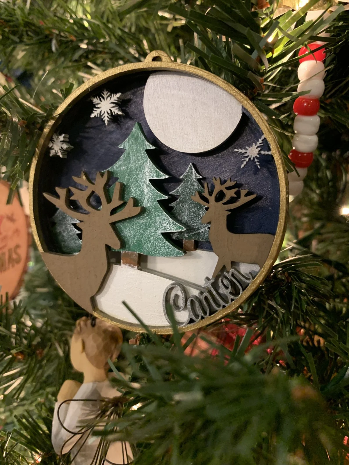 Dimensional deer and tree details inside a round Christmas ornament