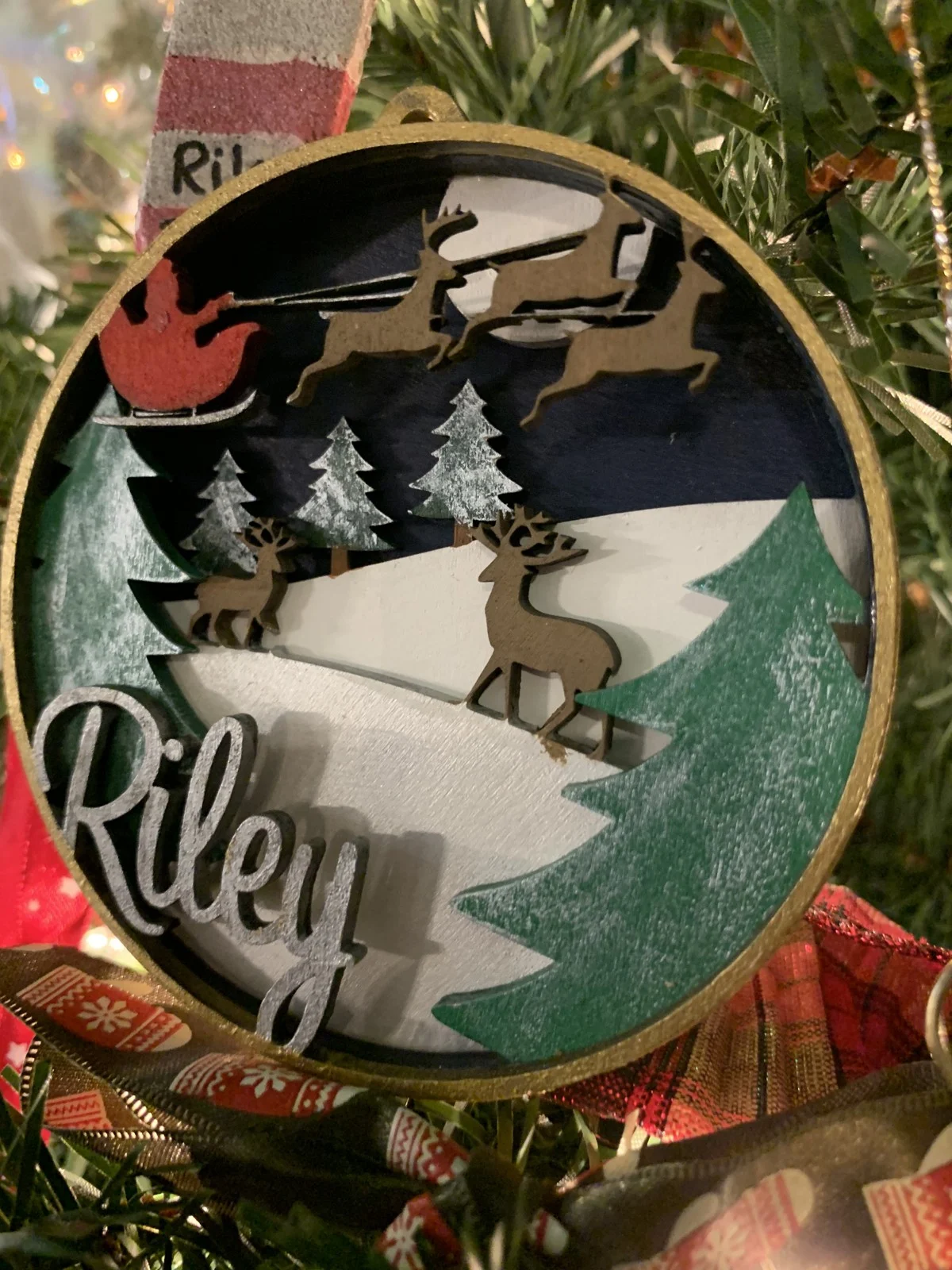 Personalized Riley ornament displayed among Christmas tree lights
