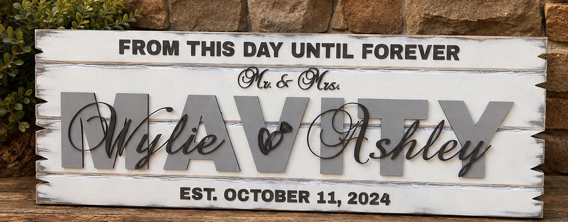 Distressed white marriage sign with a large gray family name and script first names, displayed outdoors