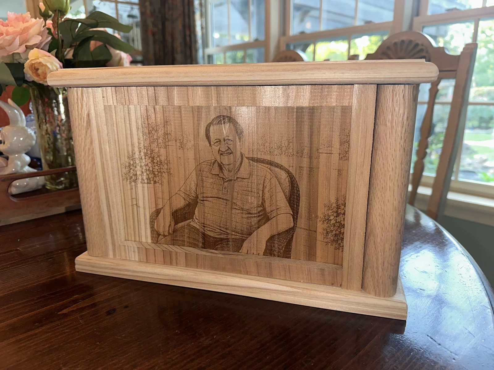 Front of a cedar urn with an engraved portrait and rounded trim
