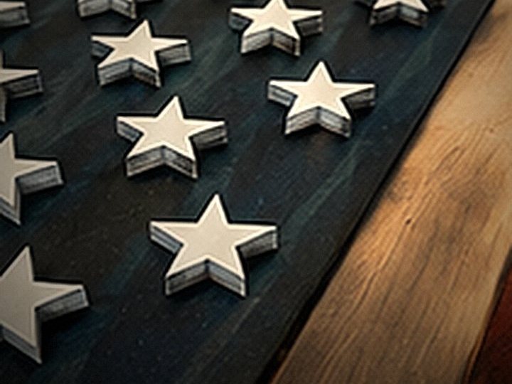 Close-up of raised white stars on the navy field of a burned-wood flag