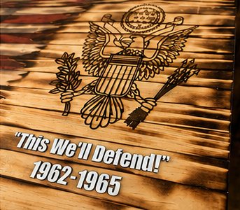 Engraved eagle with "This We'll Defend!" and 1962-1965 on burned wood