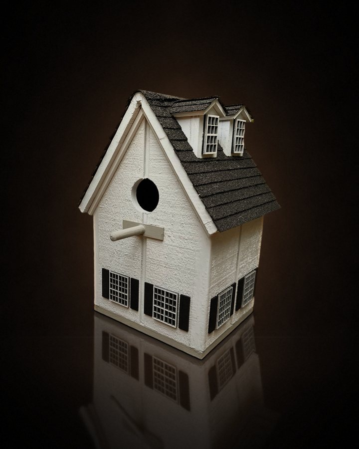 White cottage birdhouse with dormer windows and a real shingle roof
